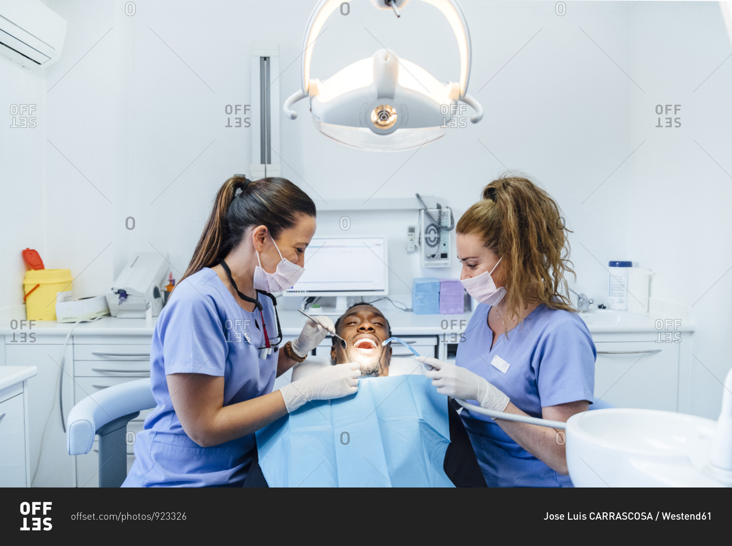 Female dentist and assistant attending patient in medical practice