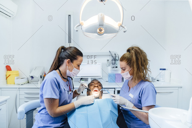 Female dentist and assistant attending patient in medical practice