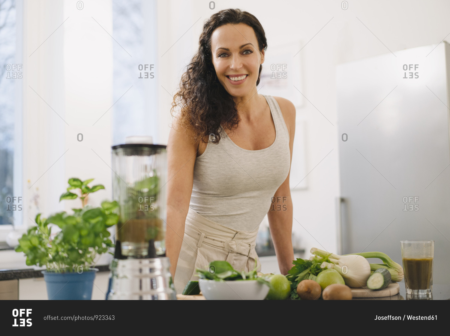Fit woman standing in kitchen- preparing healthy smoothie