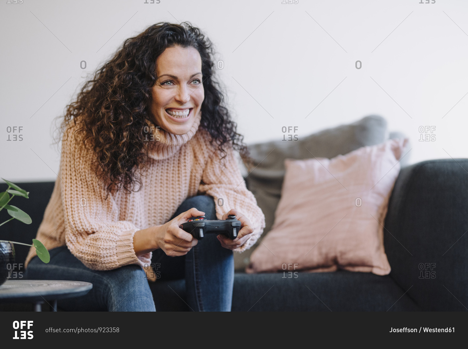 Woman sitting on couch- having fun- playing with a gaming console