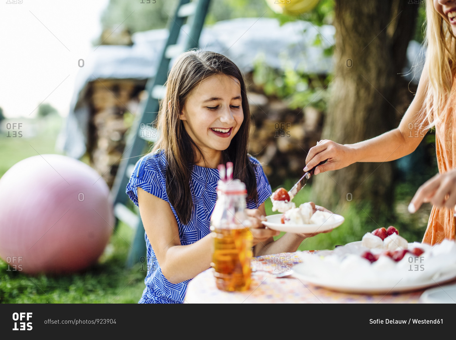 Girl receiving piece of cake on a birthday party outdoors