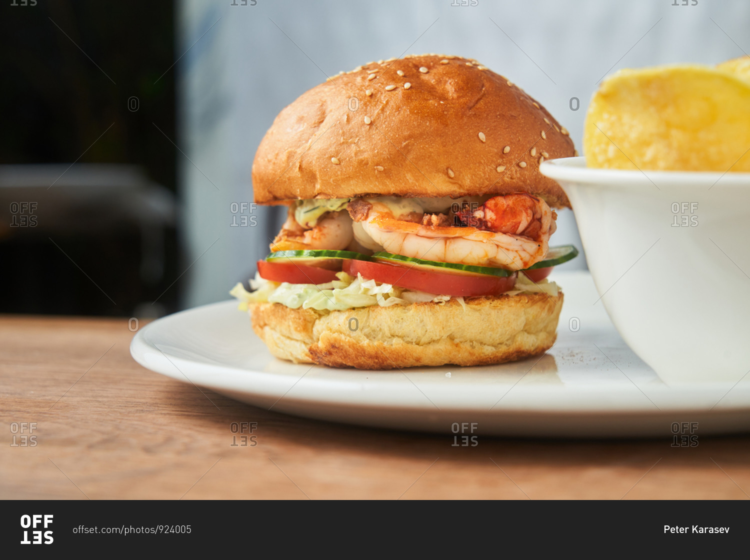 A shrimp sandwich with sesame seed bun