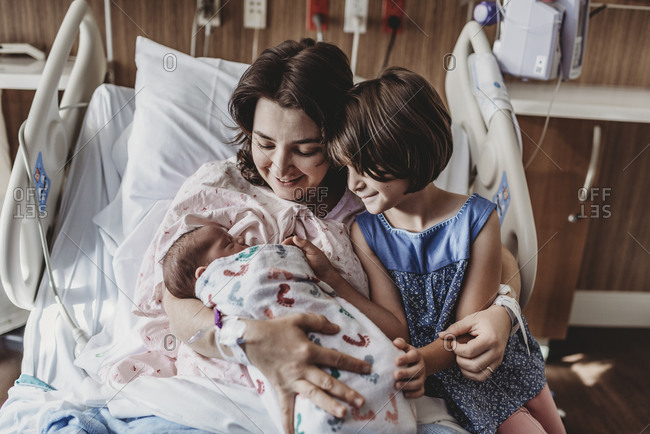 Mid view of mother holding newborn son meeting siblings
