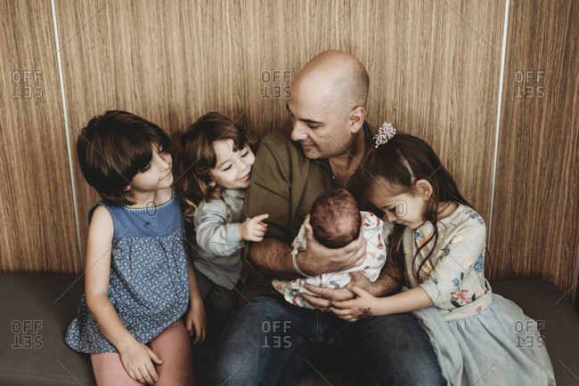 Front view of father holding newborn son with siblings