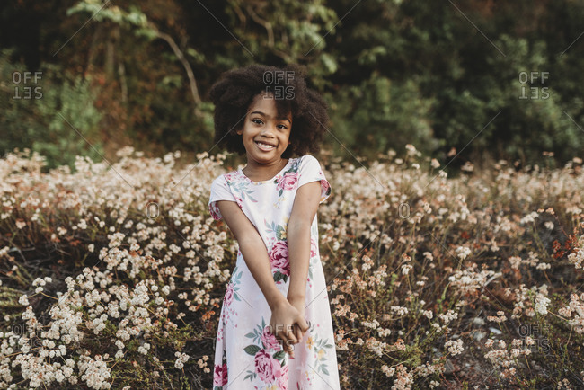Portrait of young school-aged girl smiling in field of flowers