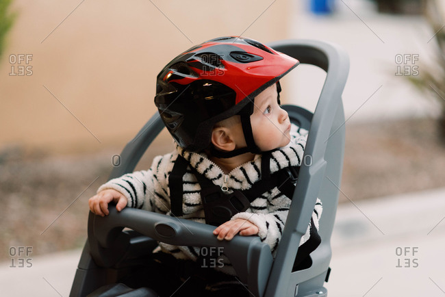 A little baby boy sitting in his bike seat.