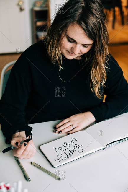 Stock photo of a lettering artist at work with her sketch book.