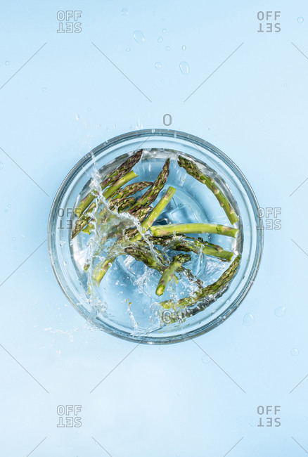 Asparagus splashing into a glass of water