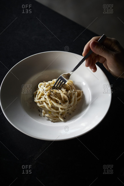 Bowl of cacio e pepe pasta on dark surface
