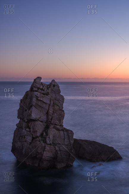 Picturesque scenery of rocks in peaceful sea and skyline in twilight in Costa Brava