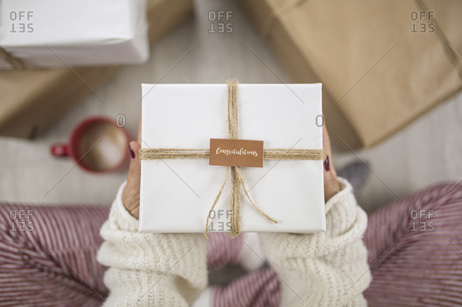 Unknown woman seated on the floor is holding a gift with an inscription that reads, Congratulations