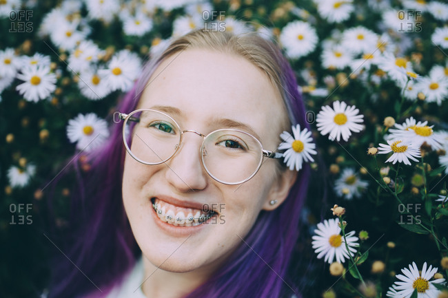 Portrait of smiling teenage girl with braces amidst daisy flowering plants
