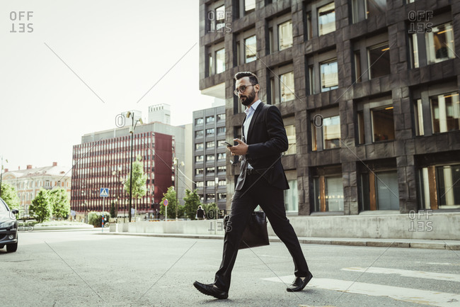 Confident businessman with bag crossing road