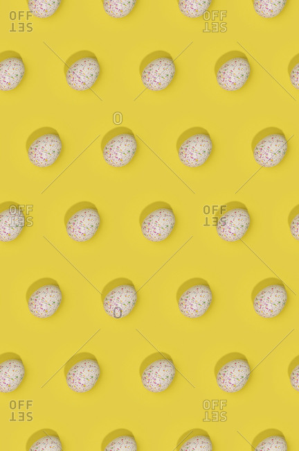 Seamless Easter pattern with colored decorated eggs arranged in rows on yellow background