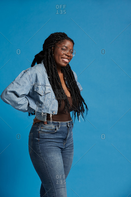 Plus size black female with braids in casual clothes smiling looking at camera sticking tongue out against blue background