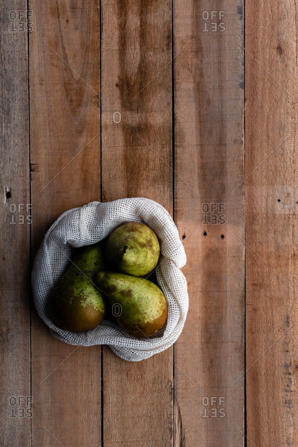 Top view of cotton sack with juicy fresh pears placed on wooden table