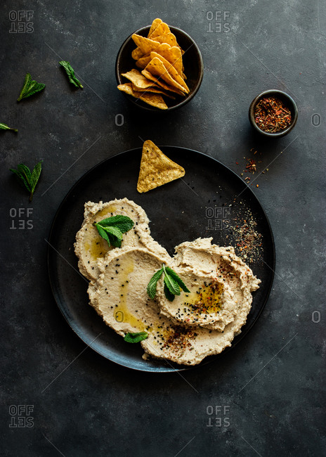 Top view of stylish black plate with delicious fresh eggplant and cauliflower dip stylish decorated with colorful spices and leaves of mint