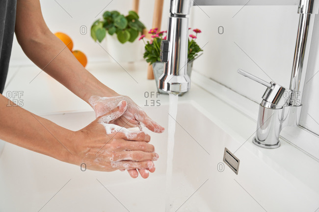 Woman washing her hands on the kitchen sink to avoid possible infection