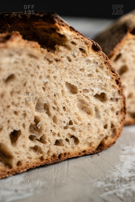 Closeup of cut fresh homemade wholegrain bread loaf with crispy crust placed on table
