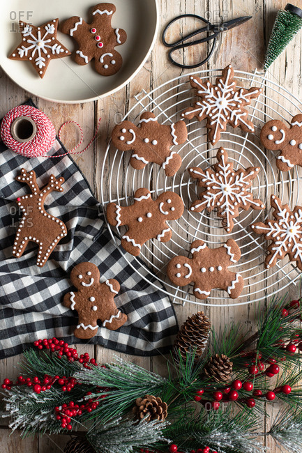 Top view of traditional homemade gingerbread with icing placed on wooden table with decorative tree branch prepared for Christmas celebration