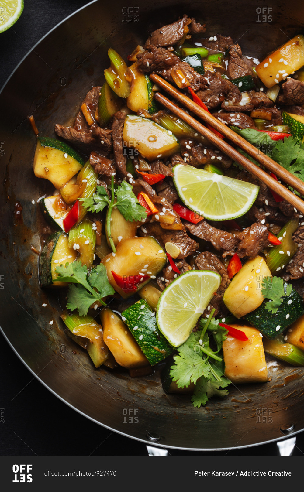 From above of Asian spicy wok stir fried dish with meat and zucchini garnished with fresh lime and cilantro