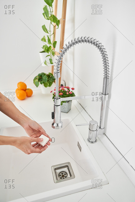 Woman washing her hands on the kitchen sink to avoid possible infection