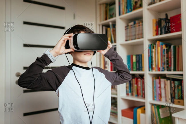 Boy wearing VR glasses with headphones. Medium shot of teenage boy wearing and touching virtual reality headset.