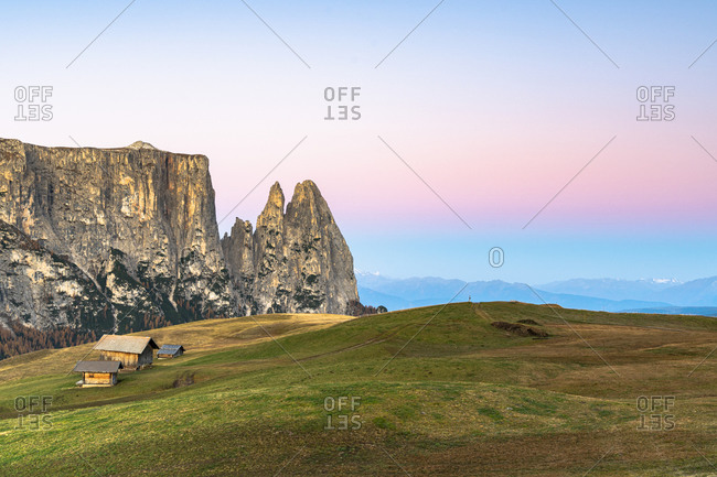 Autumn sunrise over Sciliar peaks and wood huts at Alpe di Siusi (Seiser Alm), Dolomites, South Tyrol, Italy, Europe
