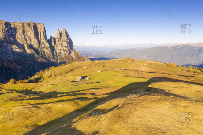 Aerial view by drone of autumn colors at Alpe di Siusi (Seiser Alm) and Sciliar peaks lit by sunrise, Dolomites, South Tyrol, Italy, Europe