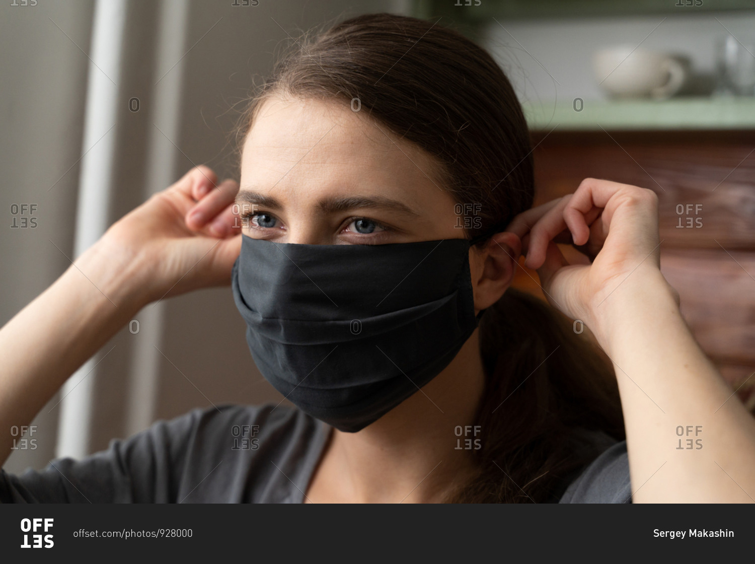 A woman holds a protective silk mask on her face to protect herself from the covid-19 virus