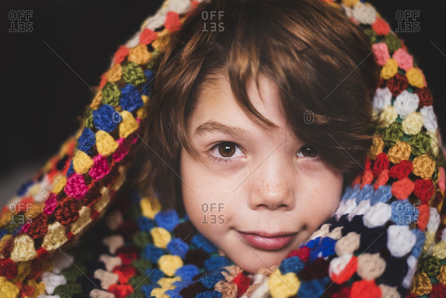 A portrait of a young boy wrapped in a colorful blanket