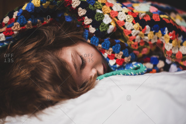 A young boy wrapped in a colorful blanket while lying down