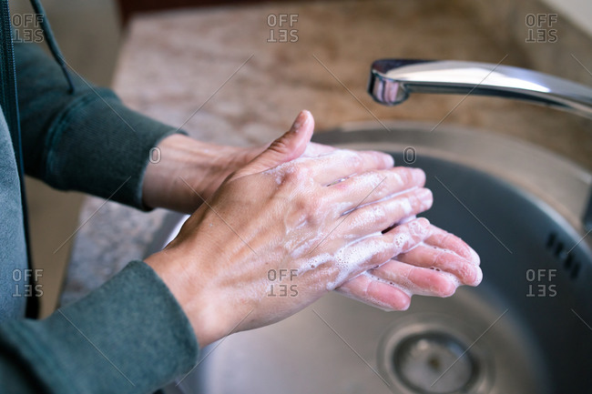 Close up of a Caucasian woman at home in bathroom during daytime washing her hands in a sink, using soap, protection against coronavirus Covid-19 infection and pandemic. Social distancing and self isolation in quarantine lockdown