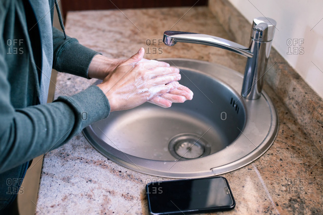 Close up of a Caucasian woman at home in bathroom during daytime washing her hands in a sink, using soap, protection against coronavirus Covid-19 infection and pandemic. Social distancing and self isolation in quarantine lockdown