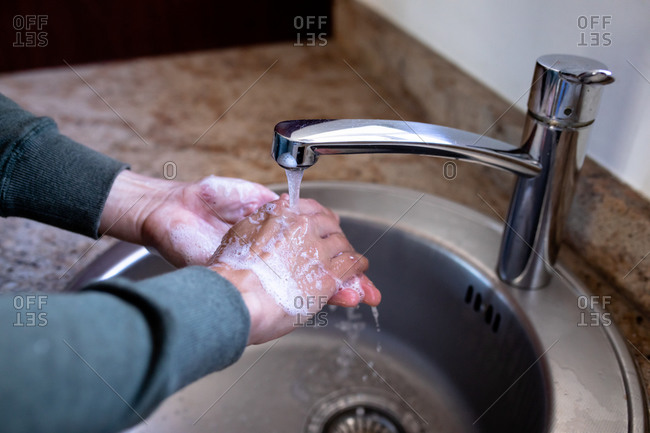 Close up of a hands of Caucasian woman at home in bathroom during daytime washing her hands in a sink, using soap, protection against coronavirus Covid-19 infection and pandemic. Social distancing and self isolation in quarantine lockdown
