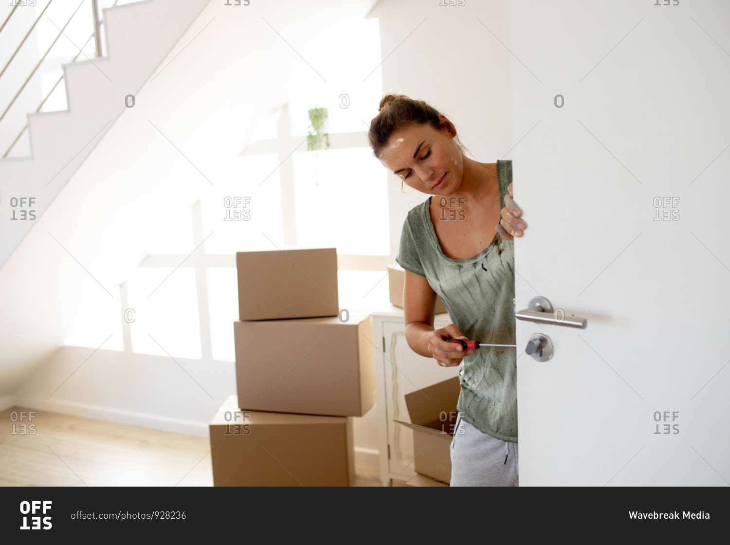 Caucasian woman spending time at home self isolating and social distancing in quarantine lockdown during coronavirus covid 19 epidemic, fixing the door while renovating her house.