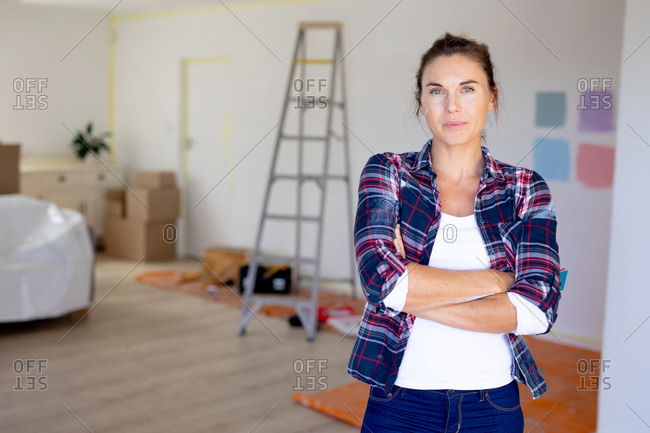 Caucasian woman spending smiling and looking straight into a camera while taking a break from renovating her home during the Covid-19 epidemic