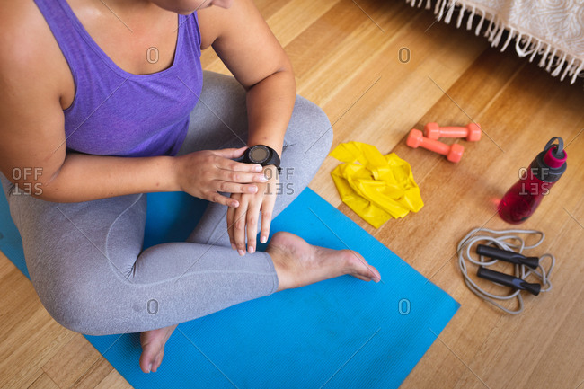 Overhead view of a female vlogger at home in her sitting room preparing to demonstrate exercises for her online blog using her smartwatch