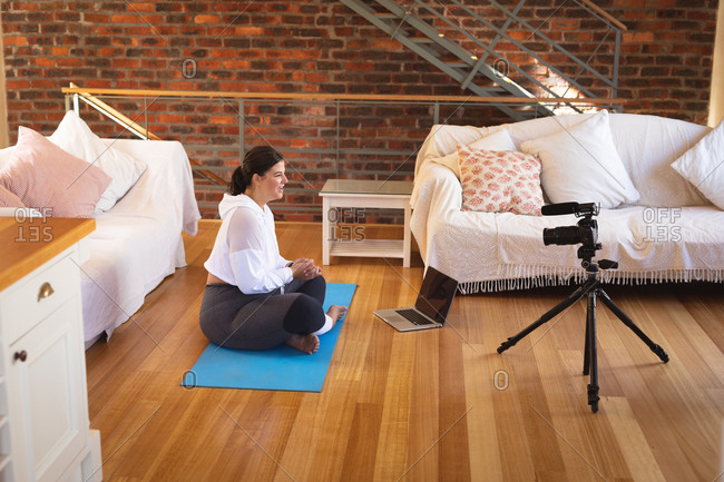 Caucasian female vlogger at home in her sitting room, demonstrating exercises for her online blog recording with a camera. Social distancing and self isolation in quarantine lockdown.