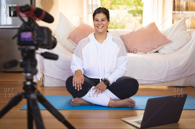 Caucasian female vlogger at home in her sitting room, demonstrating exercises for her online blog recording with a camera. Social distancing and self isolation in quarantine lockdown.