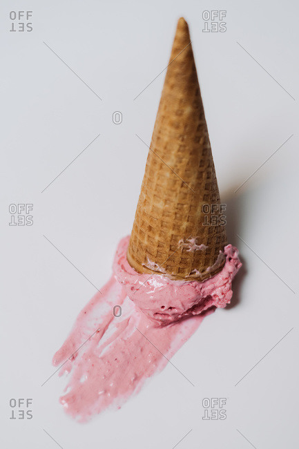 Strawberry ice cream in a cone smeared on white surface