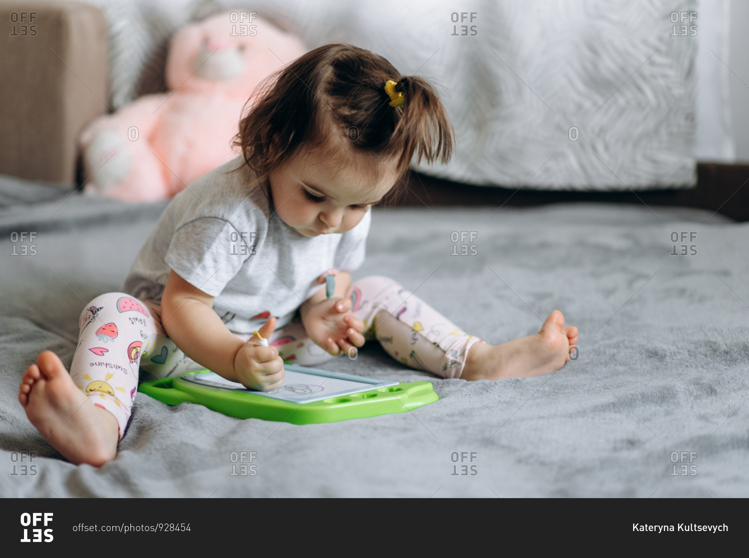 Magnetic drawing board for children. Adorable little baby girl draws on a magnetic board sitting on a sofa at home