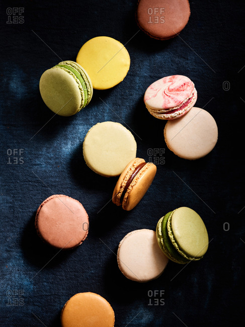 Beautiful assorted flavors of classic French macarons on dark blue textile background