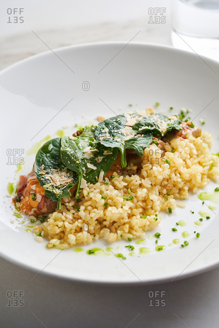 Healthy lunch with roasted chicken, baby spinach and bulgur on light marble background
