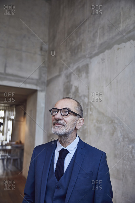 Senior businessman standing in minimalistic office- thinking