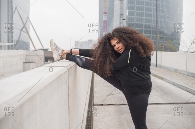 Plus size sportive young woman stretching in the city