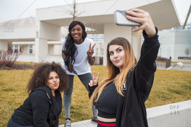 Three sportive young women taking selfie in the city