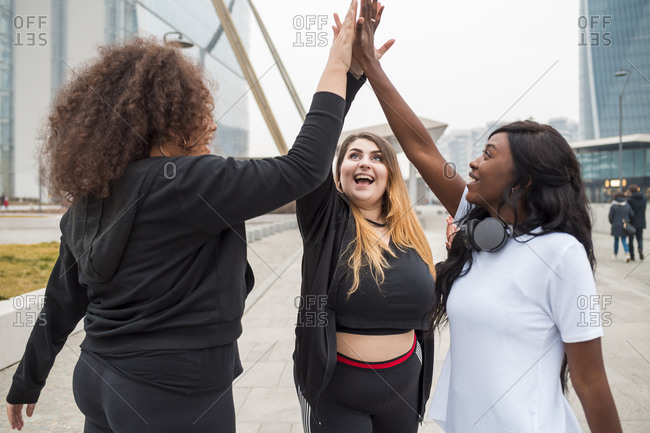 Three sportive young women high fiving in the city