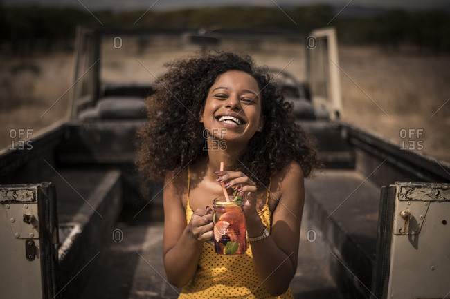 Portrait of laughing woman drinking fresh ice tea drink at safari bus