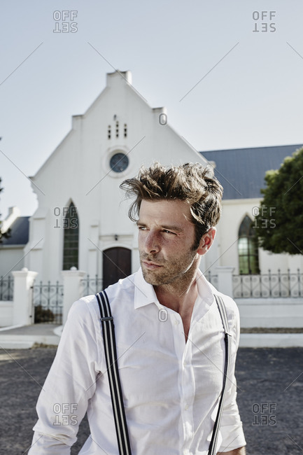 Portrait of man in old-fashioned clothes at a church in the countryside
